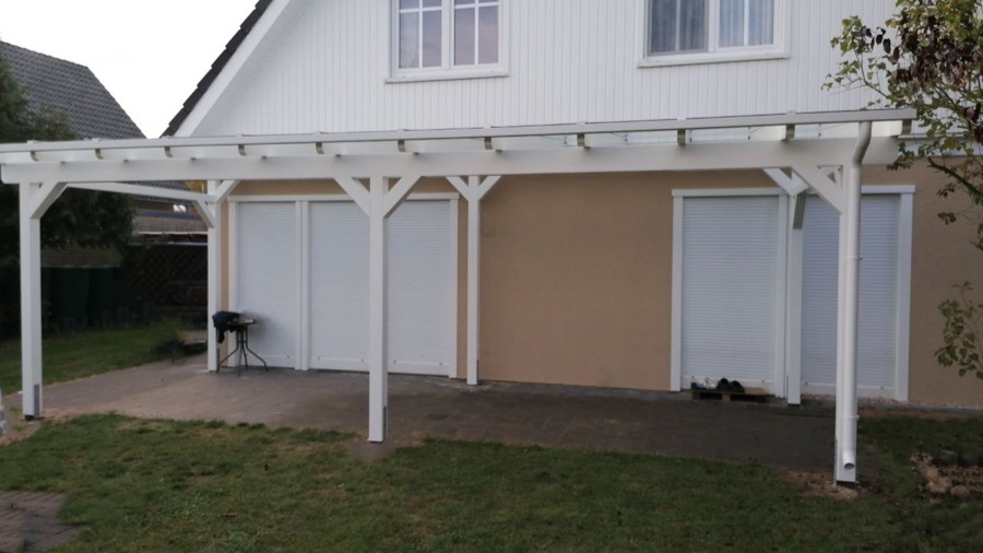 Fertiggestellte Beranda Terrassenüberdachung aus BSH-Holz, weiß deckend lackiert, als breite Anlehnüberdachung vor Garagentoren