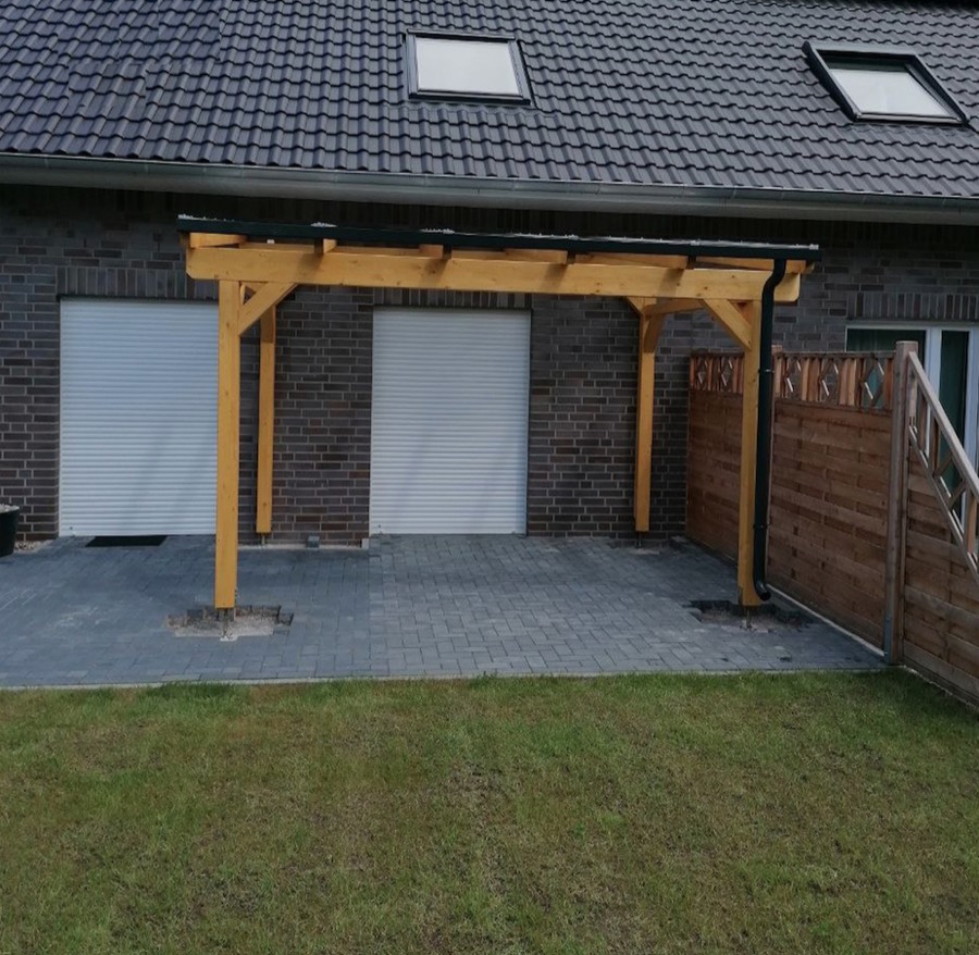 Beranda Terrassenüberdachung aus BSH-Holz in Naturton an einem Klinkerhaus neben den Garagentoren