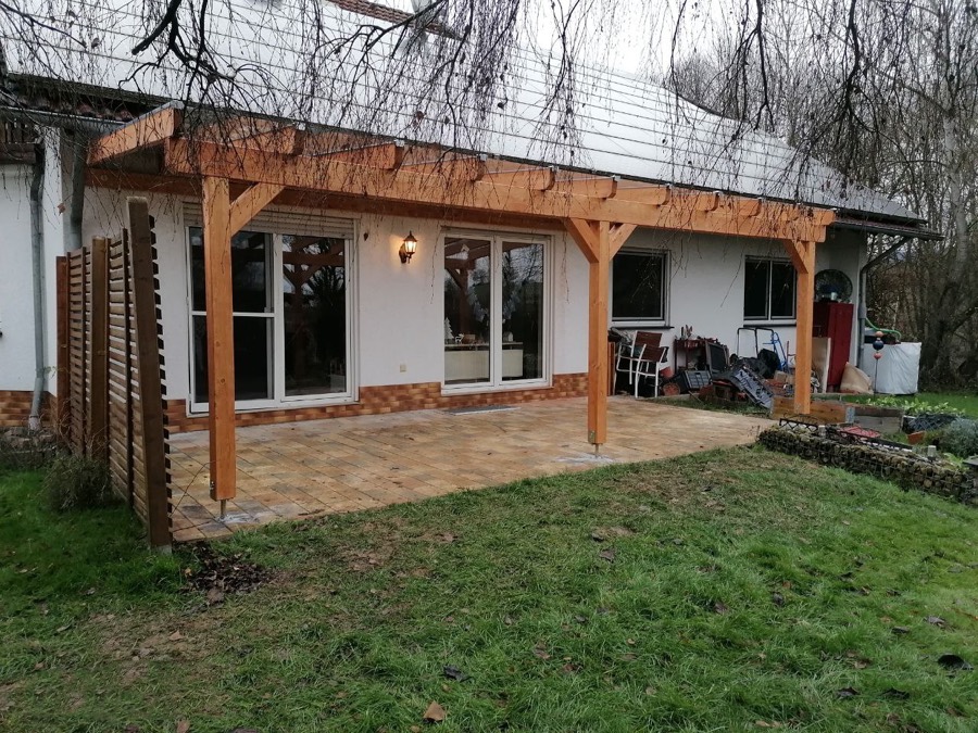 Große Beranda Terrassenüberdachung aus BSH-Holz in Naturton entlang der Fassade eines Landhauses